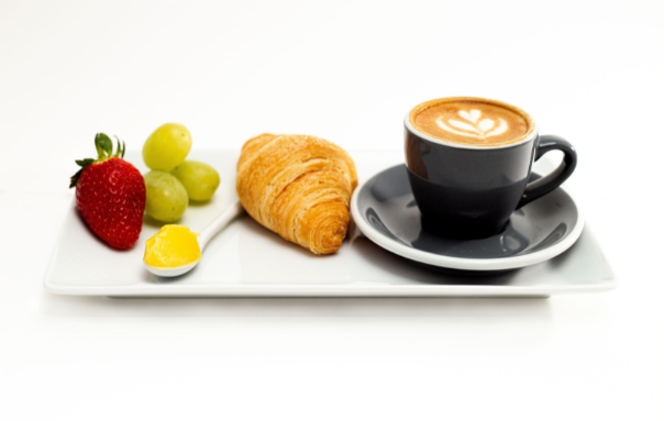Bembies Ghee on a spoon next to croissant and fruit. Coffee contains Bembies Ghee.